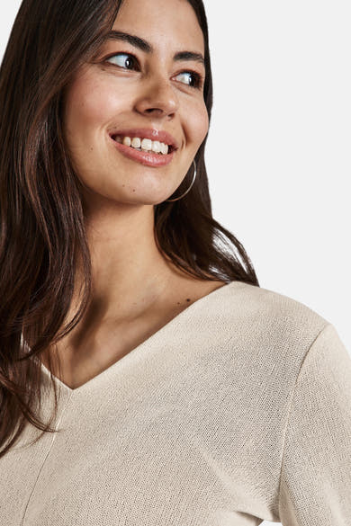 Top met lange mouwen beige van Street One, gedragen met zilveren oorbellen.