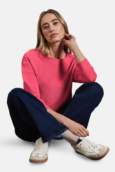 Koraalkleurig T-shirt met lange mouwen van Street One, met decoratieve knopen op de schouders, gedragen met een wijde jeans en sneakers.