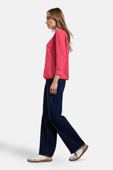 T-shirt à manches longues corail de Street One, avec boutons décoratifs sur les épaules, porté avec un jean ample et des baskets.