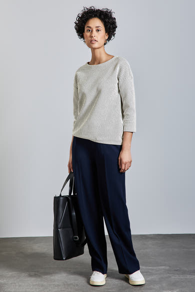 T-shirt à manches longues blanc rayé noir de Street One, porté avec un pantalon bleu marine ample et un sac noir.
