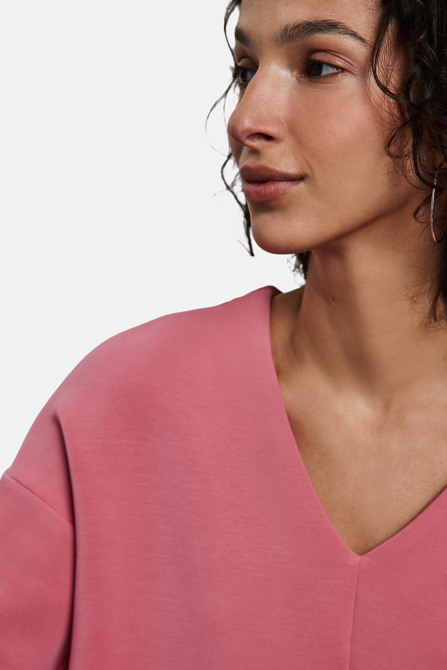 Koraalkleurig T-shirt met lange mouwen van STREET ONE, V-hals, gedragen met zilveren oorbellen.