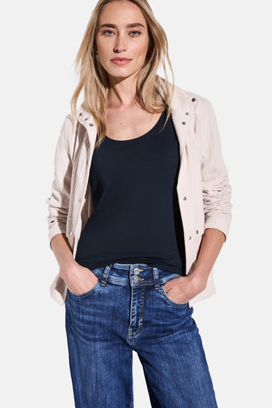 Blauwe tanktop van STREET ONE, gedragen met een beige textuurjasje en een casual spijkerbroek.