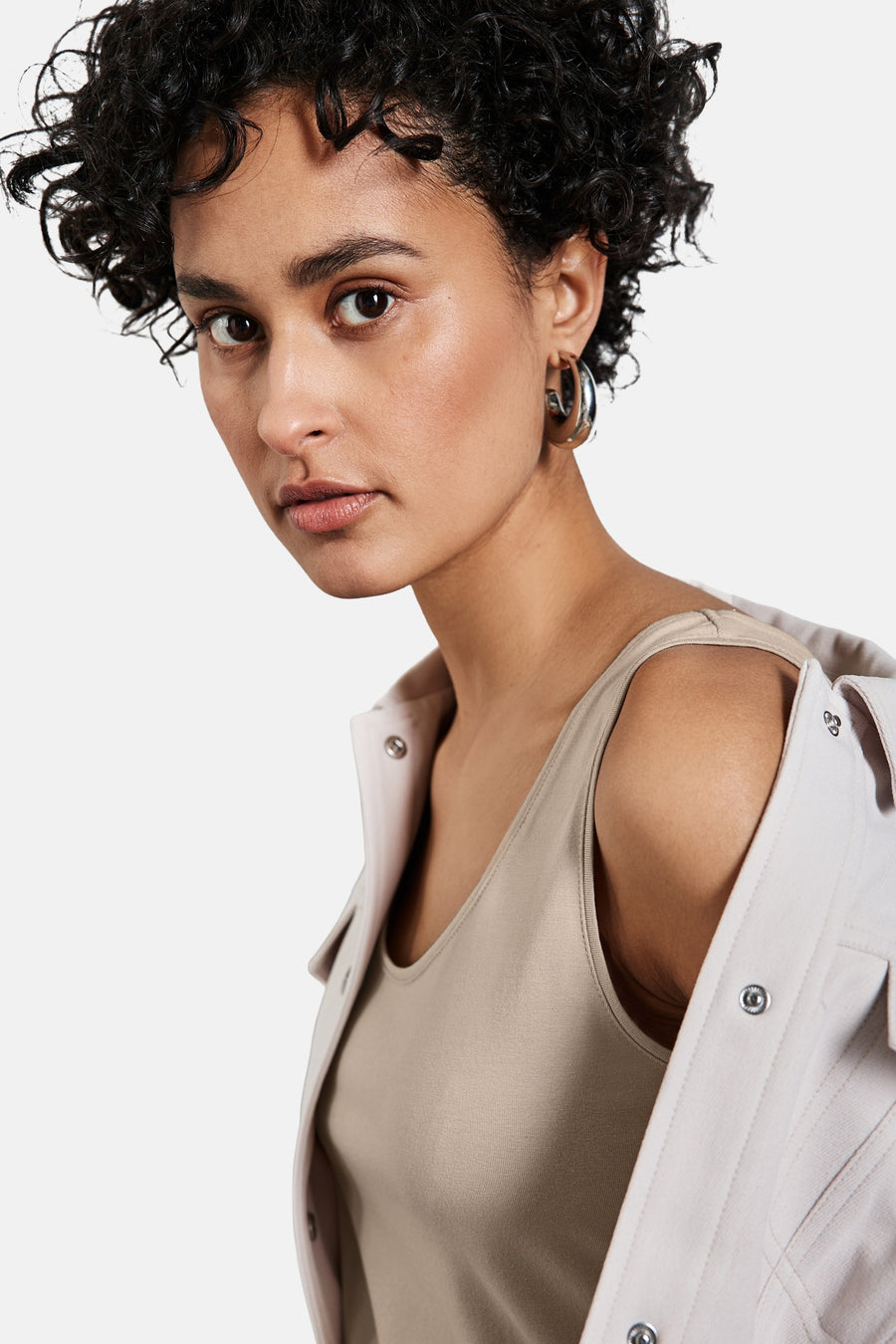 Beige tanktop van STREET ONE, gedragen met een open overhemd, gebruinde huid en krullend haar.