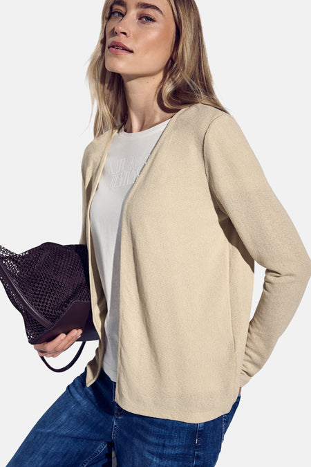Gilet beige de Street One porté sur un t-shirt blanc et un jean bleu, avec un sac à main en filet marron.