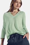 Top met lange mouwen groen, van Street One, gedragen met een wijde blauwe broek en een tas.