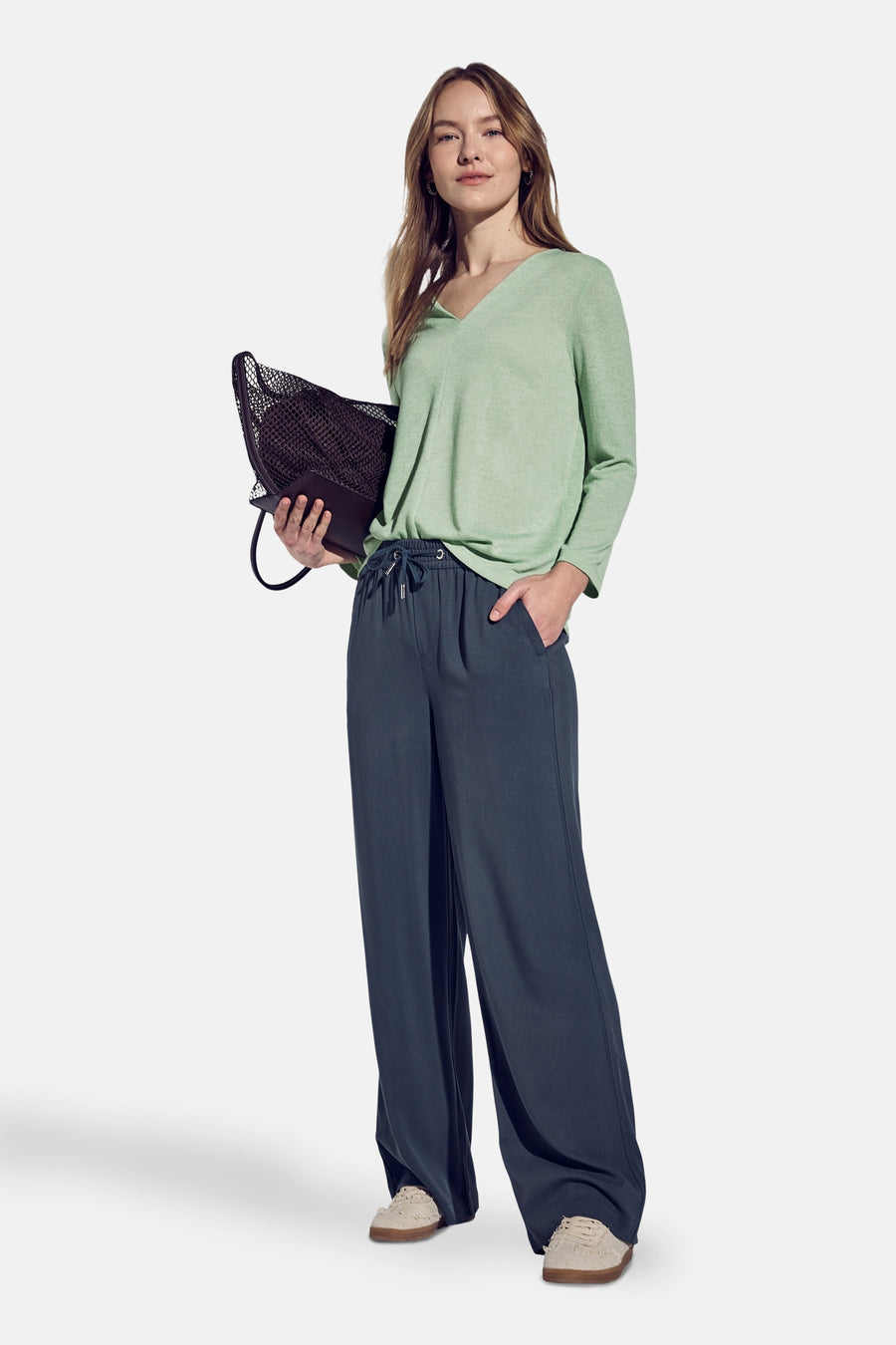 Top uni manches longues vert, de Street One, porté avec un pantalon bleu ample et un sac.
