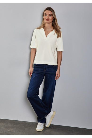 Ecru polo van STREET ONE gedragen met een donkerblauwe wijde jeans en witte sneakers.