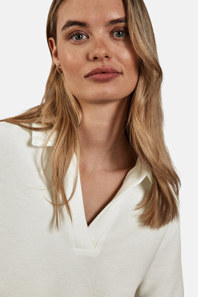 Polo écru de Street One, en maille gaufrée, avec col ouvert et cheveux blonds lâchés.