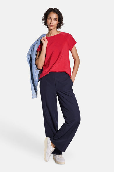 Top uni manches courtes rouge de Street One, porté avec un pantalon bleu marine ample et une veste en jean.
