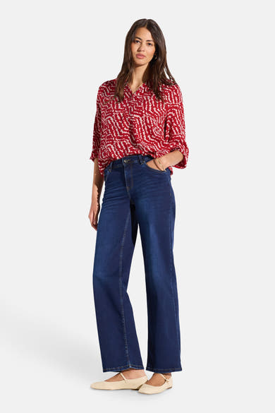 Chemisier imprimé rouge et blanc à manches longues Street One, porté avec un jean bleu large et des ballerines beiges.
