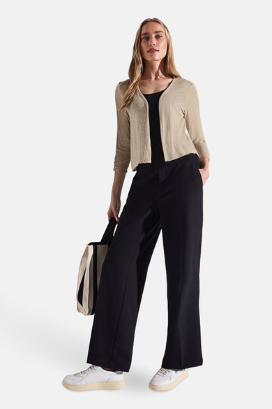 Beige gilet van Street One, gedragen over een zwarte tanktop, met een wijde broek en een gestreepte tas.