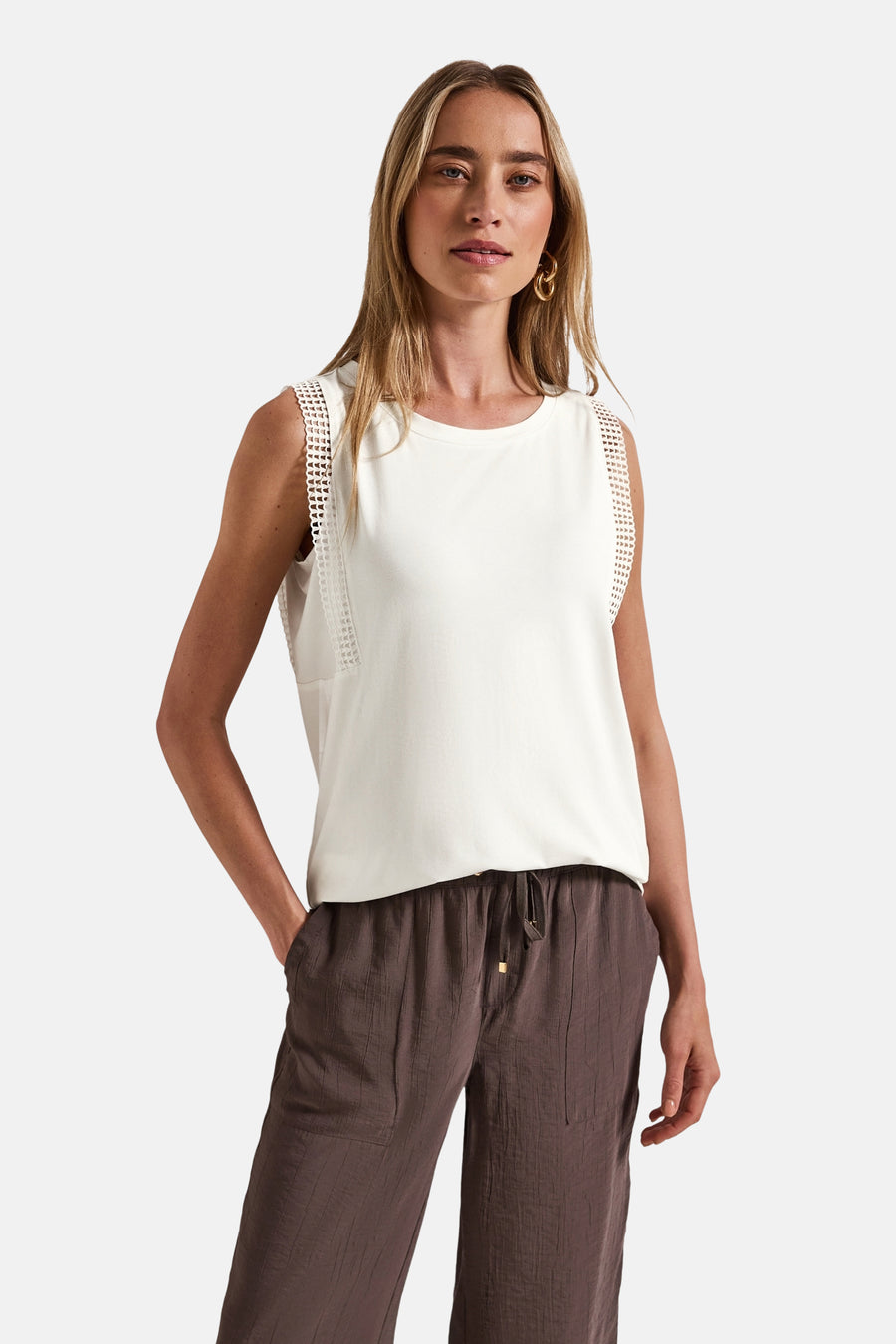 Top sans manches écru de Street One, avec détails ajourés sur les épaules et porté avec un pantalon marron.
