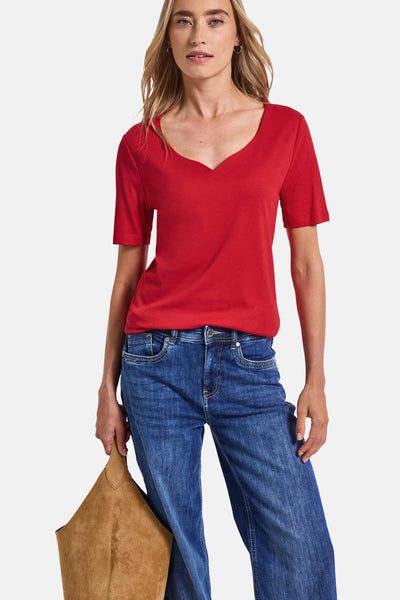 Top met korte mouwen rood van Street One, gedragen met een wijde blauwe jeans en een bruine suède tas.