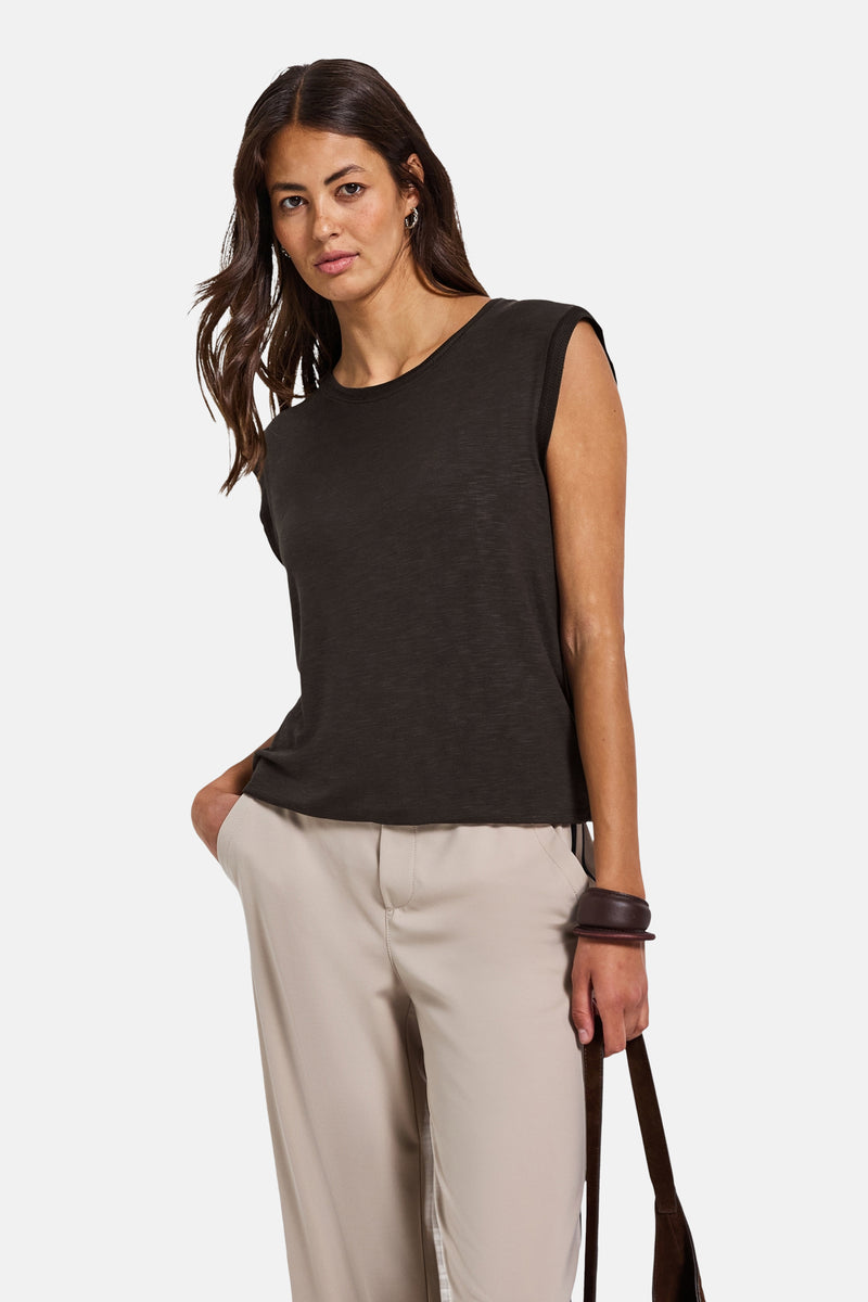 Mouwloos bruin topje van STREET ONE, gedragen met een beige broek en een bruine leren armband.