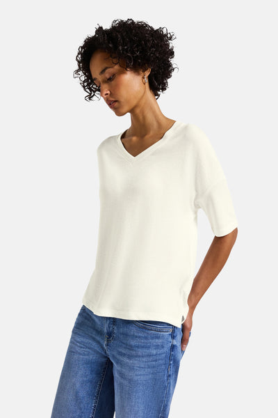 Witte V-hals trui van STREET ONE, gedragen met een blauwe jeans en gouden oorbellen.