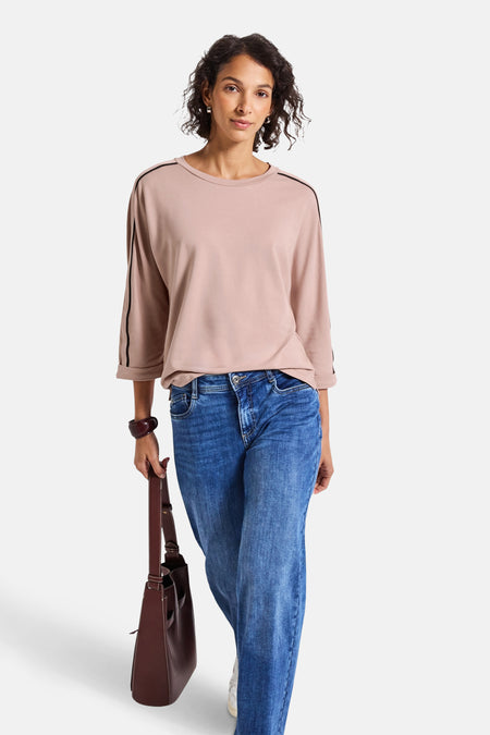 Top met lange mouwen in het roze van STREET ONE met zwarte strepen op de schouders, gedragen met een blauwe jeans en een bruine tas.
