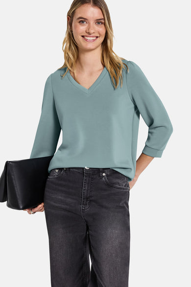 Blauwe trui van Street One, met V-hals en driekwartmouwen, gedragen met een zwarte jeans en een zwarte clutch.