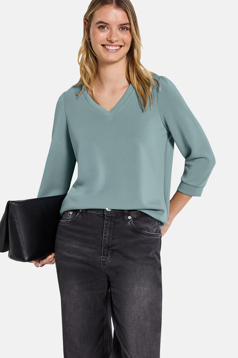 Blauwe trui van Street One, met V-hals en driekwartmouwen, gedragen met een zwarte jeans en een zwarte clutch.