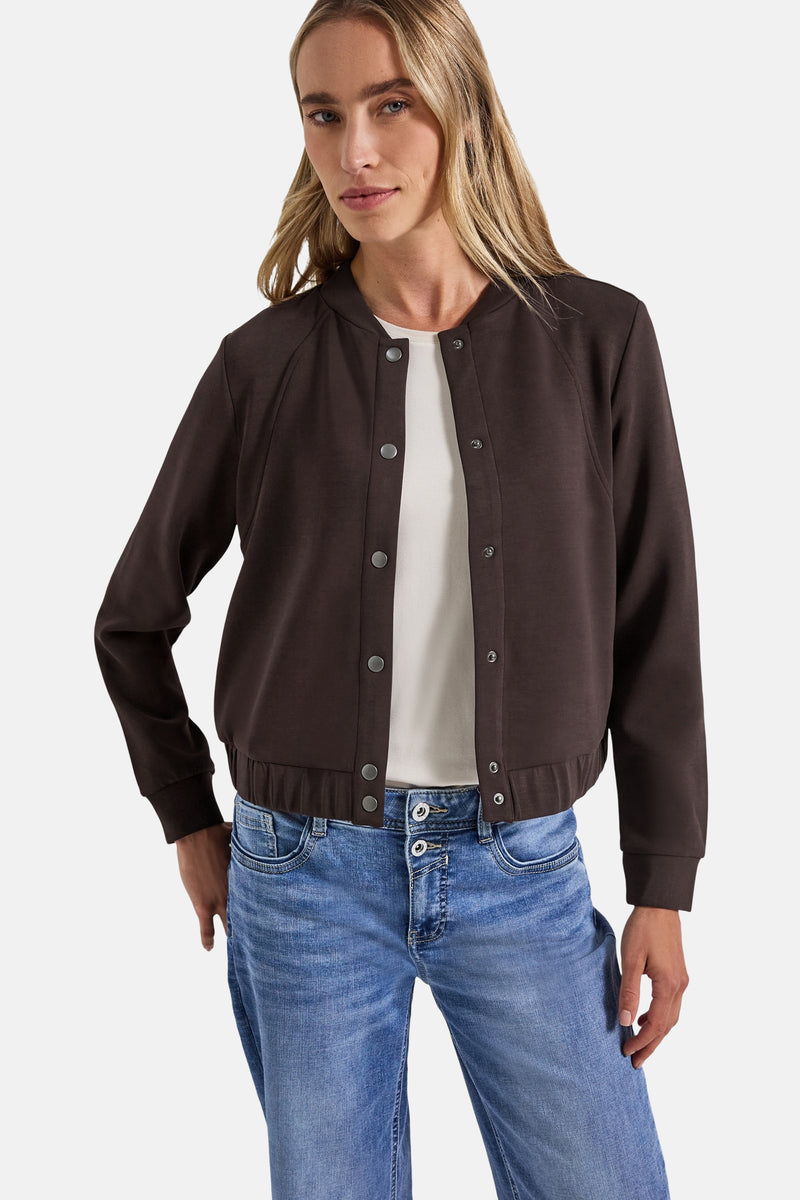 Bruin gilet van Street One met metalen drukknopen, gedragen over een wit T-shirt en een blauwe jeans.