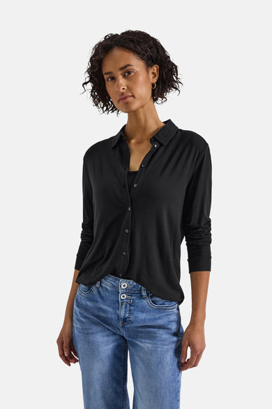Top met lange mouwen in zwart van STREET ONE, gedragen met een blauwe jeans met hoge taille en gouden oorbellen.