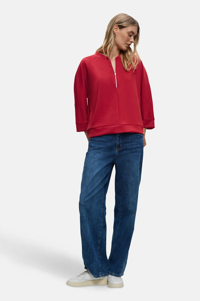 Rode sweater met rits van Street One, gedragen met een wijde jeans en witte sneakers.