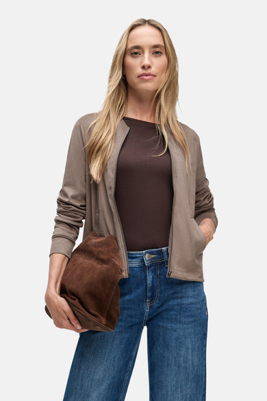 Bruine Street One-cardigan, gedragen over een bruine top en een blauwe jeans, met een bruine suède tas.