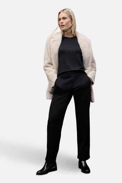 Top uni manches longues noir de Street One, porté avec un manteau en fausse fourrure crème et un pantalon noir.