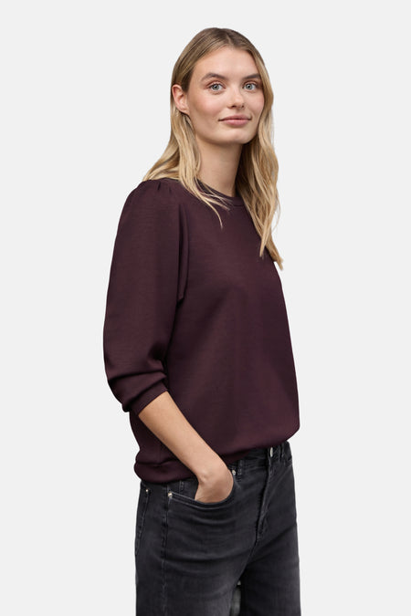 Sweat col rond rouge de Street One, porté avec un jean noir délavé.
