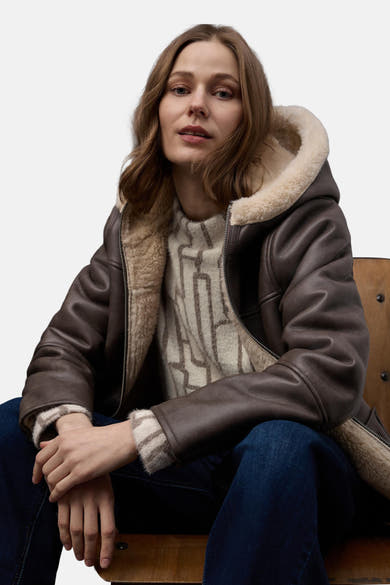 Pull col rond beige de STREET ONE avec motif géométrique et manches longues, porté avec un blouson aviateur en cuir marron.
