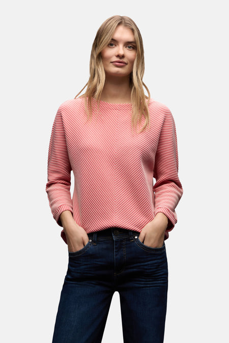 Top uni manches longues corail de STREET ONE, porté avec un jean foncé, mains dans les poches.