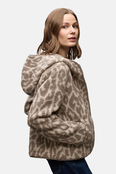 Korte beige jas van STREET ONE met een getextureerd dierenprint, gedragen met een wijde jeans en een bruine tas.