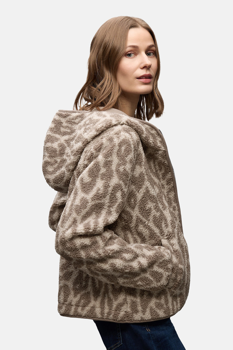 Korte beige jas van STREET ONE met een getextureerd dierenprint, gedragen met een wijde jeans en een bruine tas.