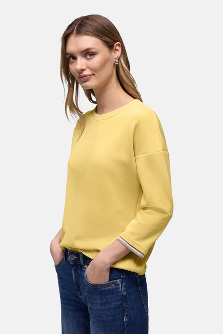 Gele trui van STREET ONE met een beige en witte gestreepte boord, gedragen met een blauwe jeans.