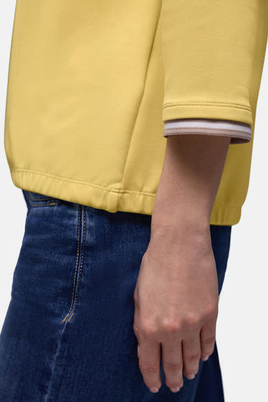 Sweat jaune de STREET ONE avec un poignet rayé beige et blanc porté avec un jean bleu.
