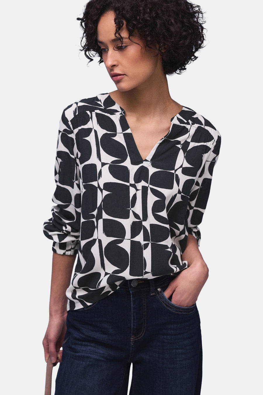 Multikleurige blouse van Street One, met geometrische patronen, gedragen met een donkerblauwe jeans en grijze schoenen.