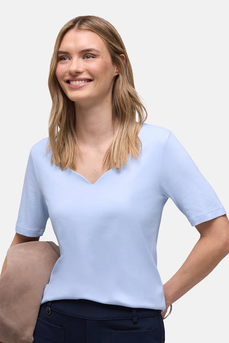 Effenchemise Street One effen blauw met korte mouwen, gedragen met een marineblauwe broek en een beige jasje.