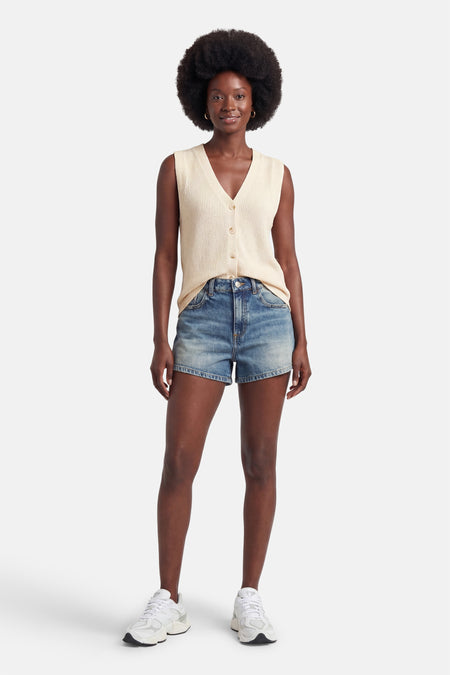 Gilet écru côtelé de STREET ONE avec col en V et boutons, porté avec un short en jean et des baskets blanches.