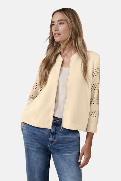 Gilet beige de STREET ONE avec manches ajourées et porté sur un top uni et un jean.