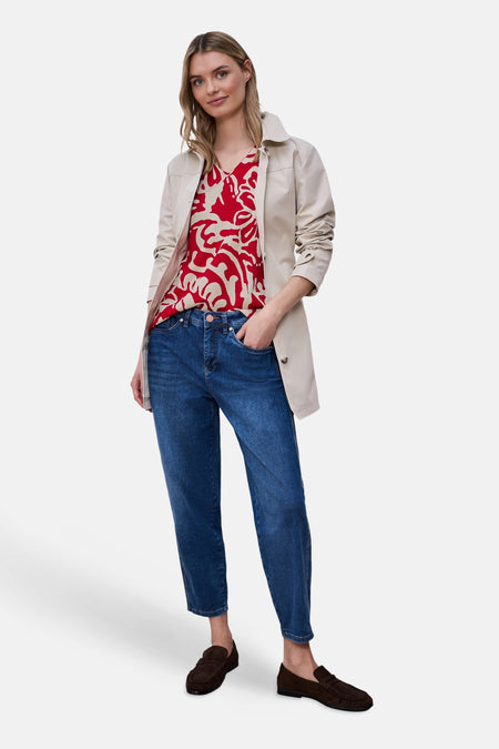 Blouse rouge à manches courtes de Street One, avec un motif abstrait rouge et beige, portée sous une veste beige et un jean bleu.
