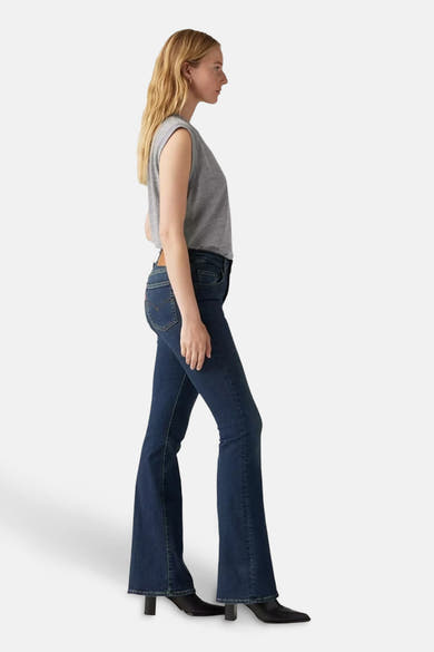 Uitlopende jeans in donkerblauw denim van Levi's®, gedragen met een grijs T-shirt en zwarte enkellaarsjes.
