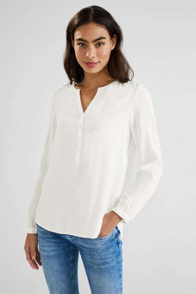 Chemisier blanc à manches longues par STREET ONE, avec patte de boutonnage et porté avec un jean bleu.
