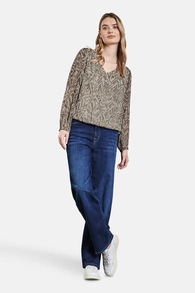 Chemisier beige à manches longues de Street One, imprimé avec un motif abstrait et porté avec un jean.
