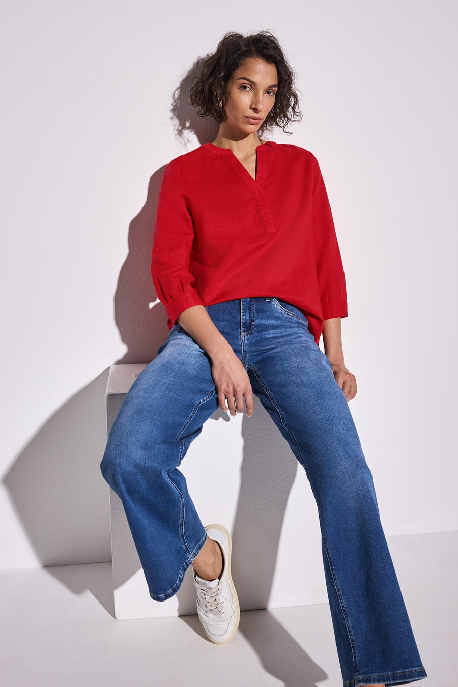 Blouse rouge à manches longues de STREET ONE, portée avec un jean bleu évasé et des baskets blanches.