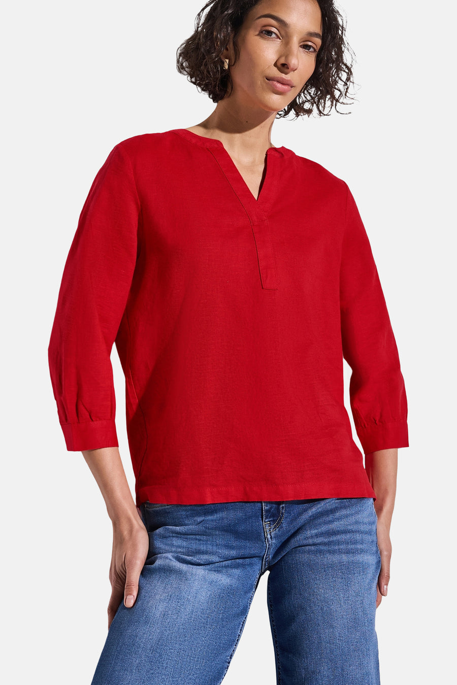 Blouse rouge à manches longues de Street One, avec un col en V et portée avec un jean bleu.
