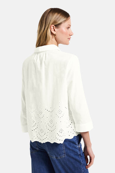 Chemisier blanc à manches longues de STREET ONE, avec broderie anglaise sur le bas, porté avec un jean bleu.
