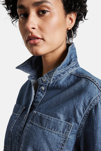 Middelblauwe spijkerblouse van STREET ONE, met kraag en borstzak, gedragen met oorringen.