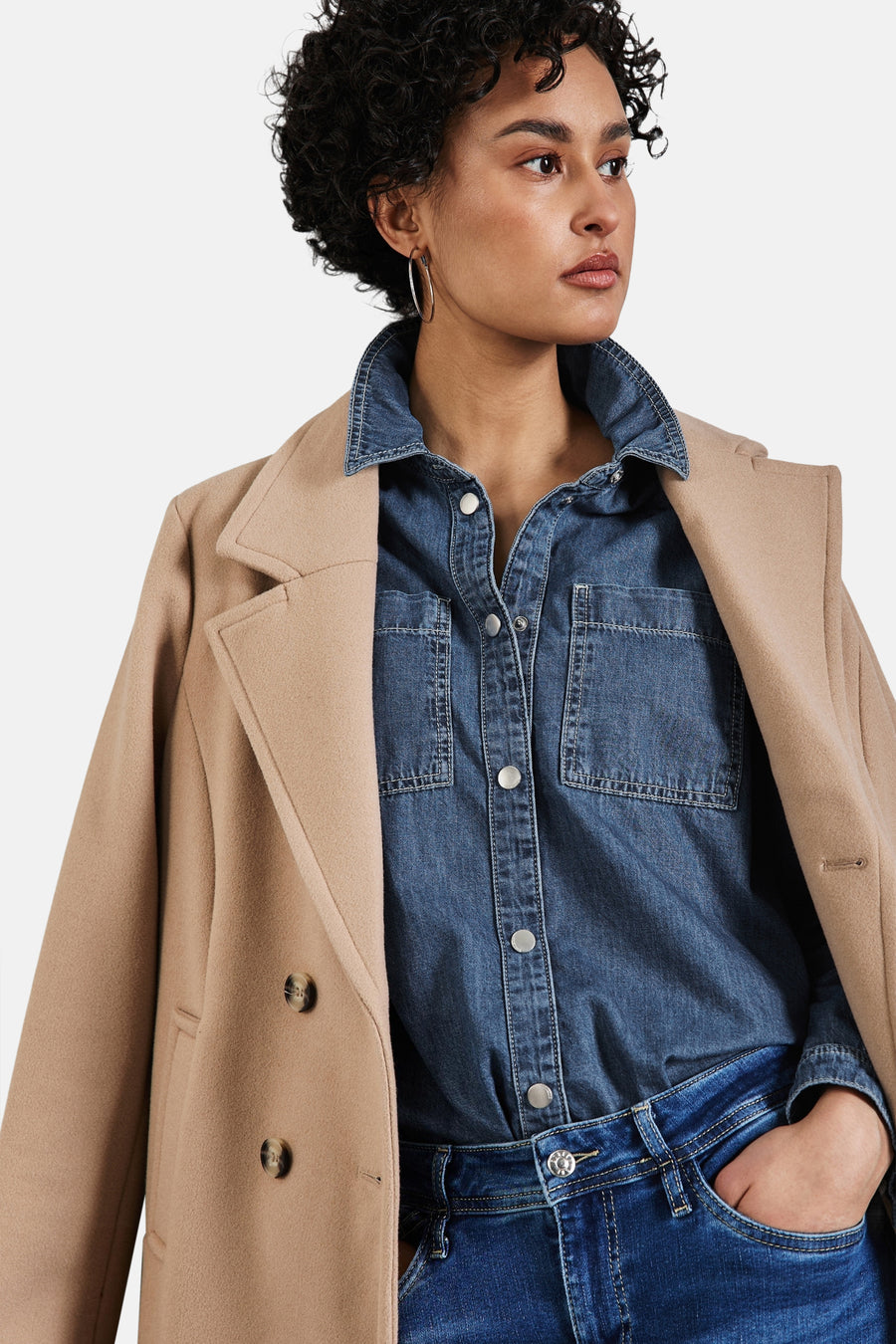 Blouse met lange mouwen in denimblauw van STREET ONE, gedragen met een beige jas en een blauwe jeans.