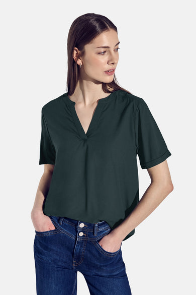 Chemisier vert à manches courtes de STREET ONE, avec encolure en V, porté avec un jean taille haute bleu.
