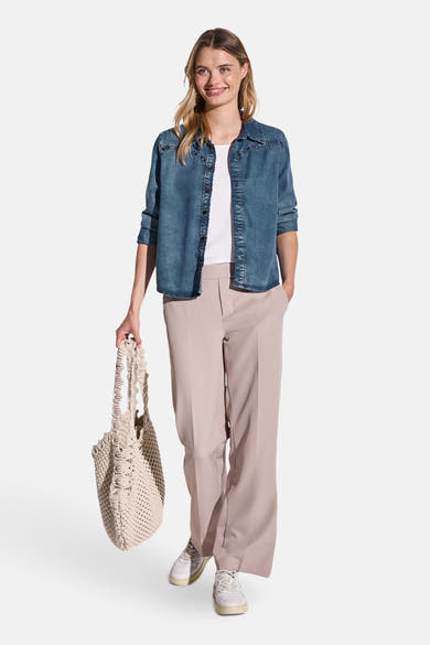 Blouse met lange mouwen in middieblauw denim van STREET ONE, gedragen open over een wit T-shirt en een beige broek.
