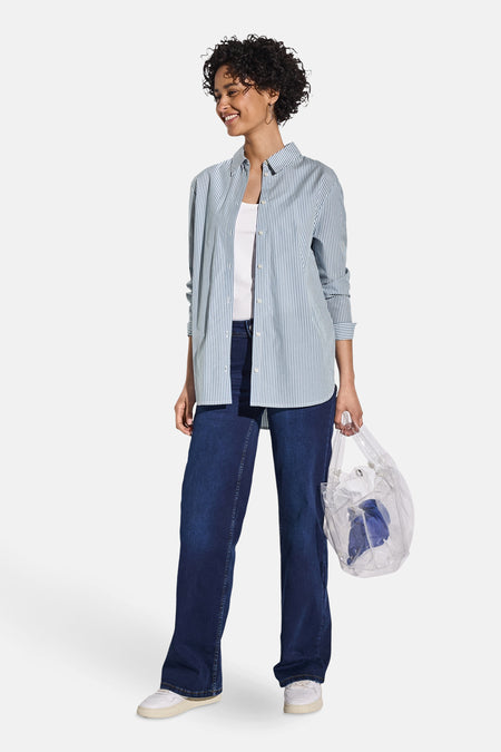 Chemisier bleu à rayures verticales de Street One, porté ouvert sur un débardeur blanc, avec un jean large et un sac transparent.
